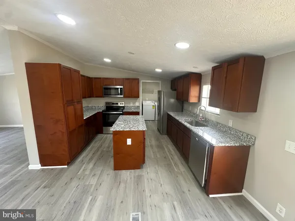 a kitchen with stainless steel appliances granite countertop a refrigerator a sink dishwasher a stove with wooden floors and cabinets