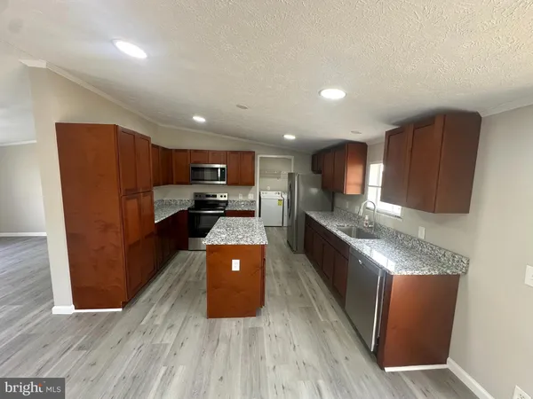 a large kitchen with stainless steel appliances granite countertop wooden cabinets a granite counter tops and a hard wood floors