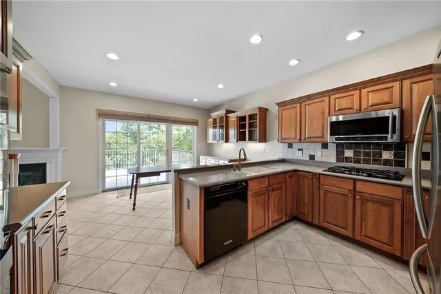 a kitchen with stainless steel appliances granite countertop a stove top oven a sink dishwasher a dining table and chairs with wooden floor