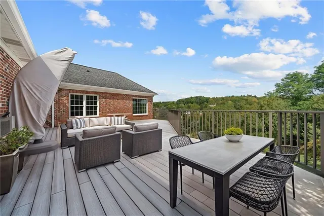 a view of a roof deck with table and chairs couches with wooden floor