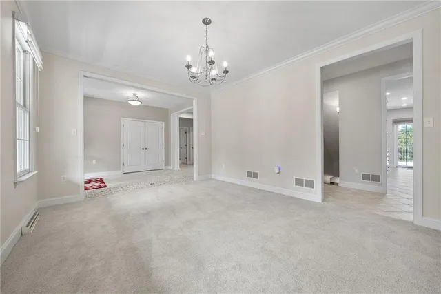 an empty room with chandelier fan and windows