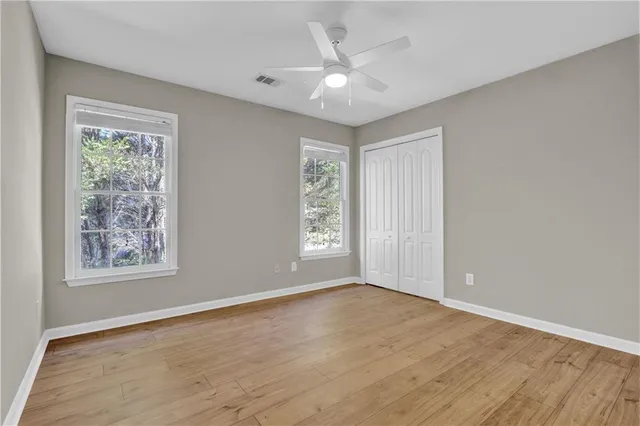 a view of an empty room with a window and wooden floor