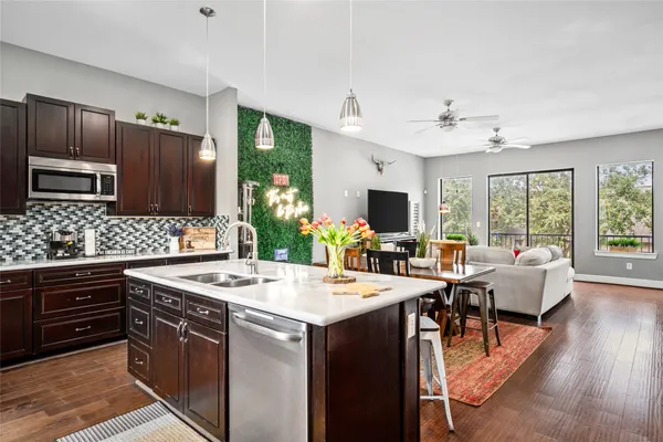 a kitchen with a stove a sink dishwasher a refrigerator and a dining table with wooden floor