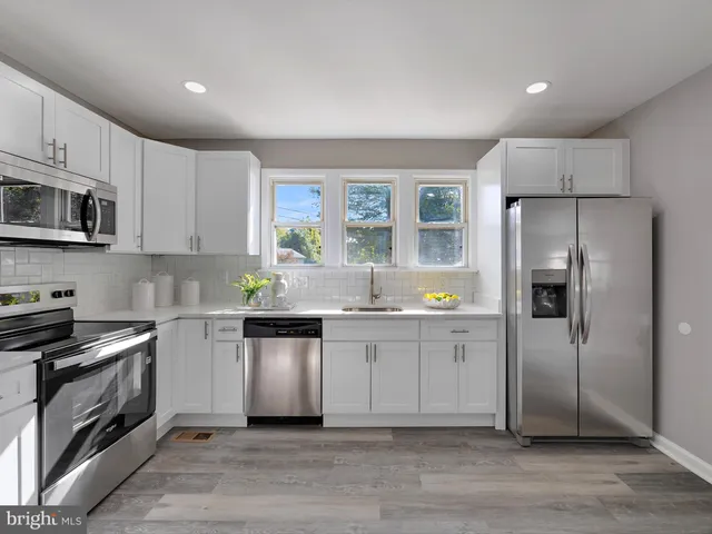 a kitchen with granite countertop a refrigerator stove and sink