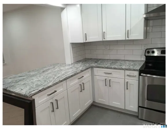 a kitchen with granite countertop white cabinets and white appliances