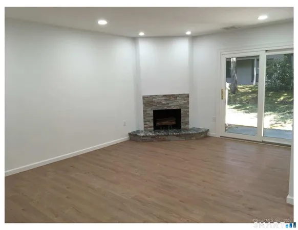 a view of an empty room with wooden floor and a fireplace