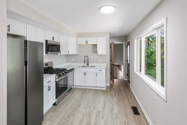 a kitchen with white cabinets and stainless steel appliances