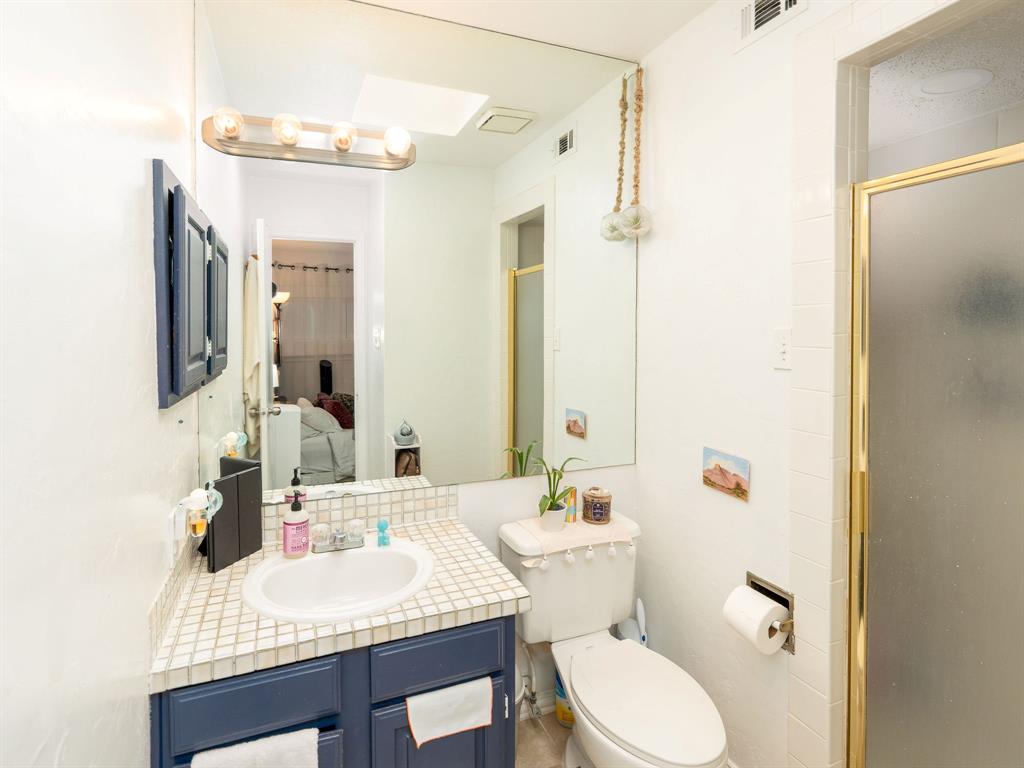 18240 Midway Road, Unit 205 Dallas, TX 75287 - Photo 20 of 27 a bathroom with a granite countertop sink toilet a mirror and shower