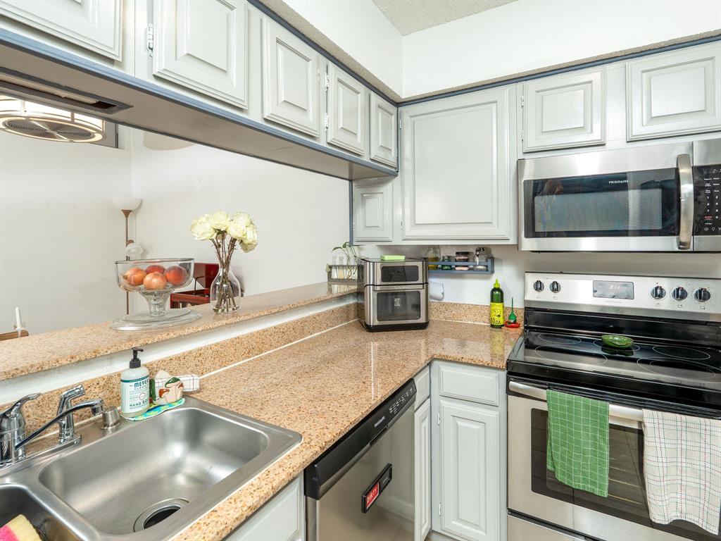 18240 Midway Road, Unit 205 Dallas, TX 75287 - Photo 5 of 27 a kitchen with kitchen island a sink stove top oven and microwave