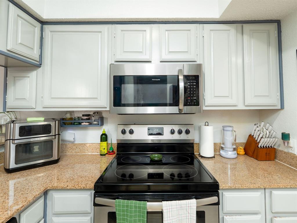 18240 Midway Road, Unit 205 Dallas, TX 75287 - Photo 6 of 27 a kitchen with stainless steel appliances granite countertop white cabinets and a stove a oven with white countertops