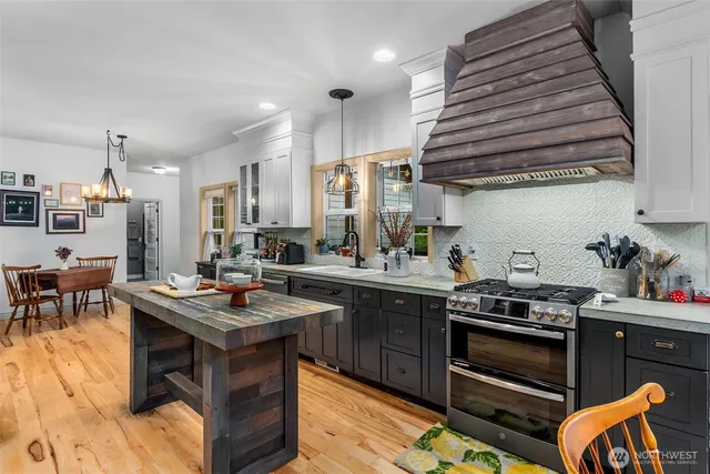 a kitchen with stainless steel appliances granite countertop a stove a sink dishwasher and cabinets with wooden floor