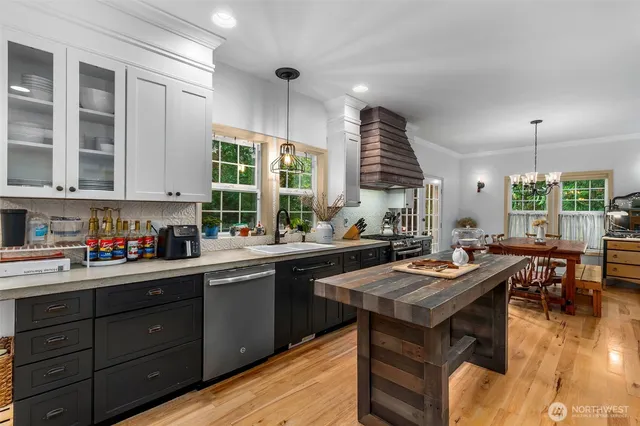 a kitchen with a stove a sink dishwasher cabinets and dining table with wooden floor
