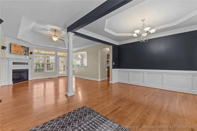 a view of an empty room with wooden floor and a fireplace