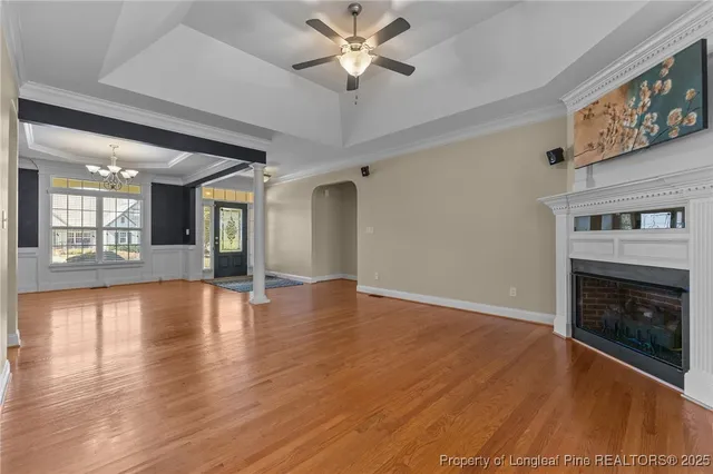 a view of an empty room with wooden floor and a fireplace