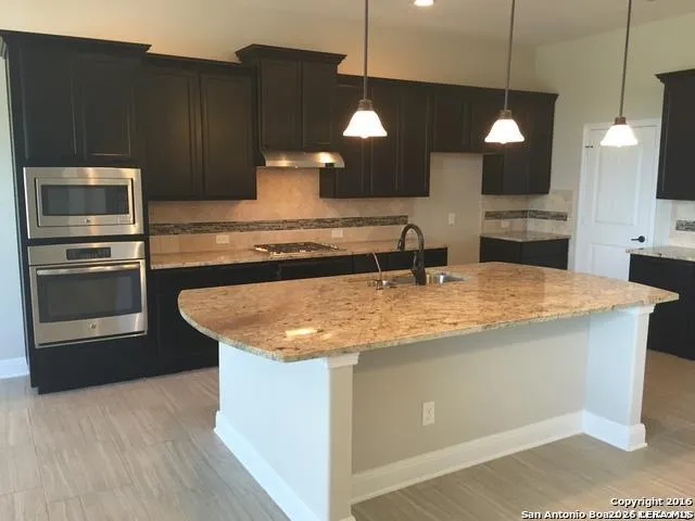 a kitchen with stainless steel appliances granite countertop a sink a microwave and wooden cabinets
