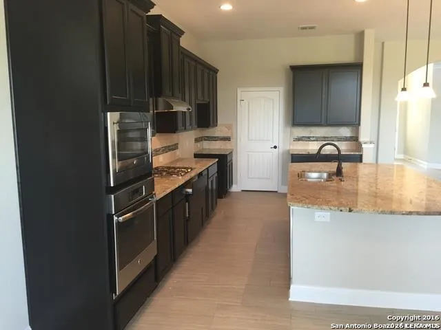 a kitchen with kitchen island granite countertop a sink stove and refrigerator
