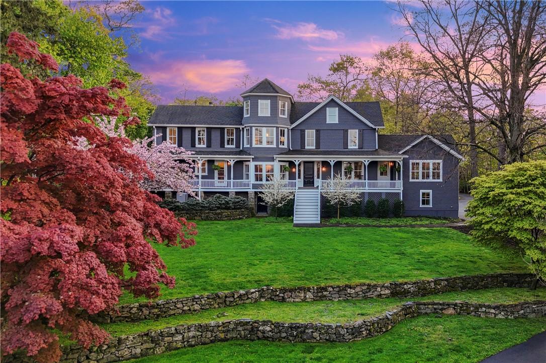 a view of a house next to a big yard and large trees