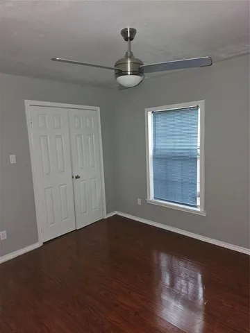 an empty room with wooden floor cabinet and windows
