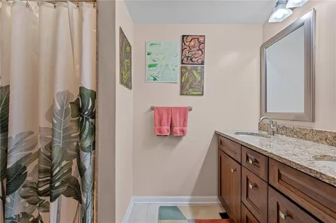 a bathroom with a granite countertop sink a mirror and shower curtain