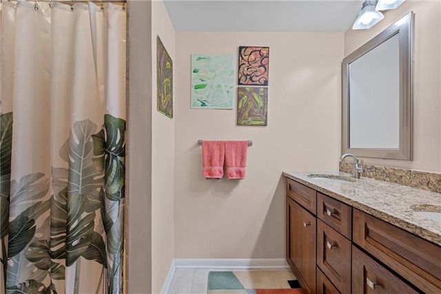 a bathroom with a granite countertop sink a mirror and shower curtain