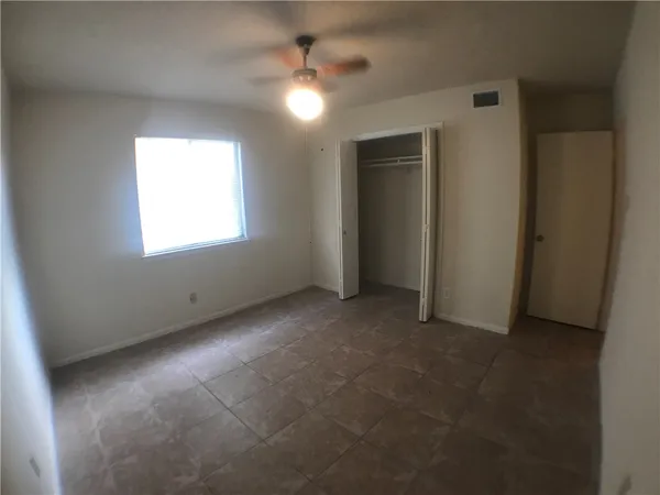 an empty room with windows and fan