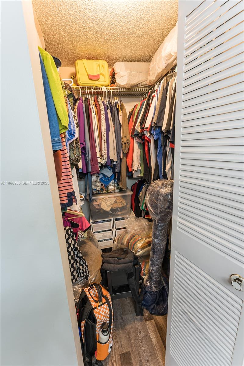 8810 Southwest 132nd Place, Unit 404DN Miami, FL 33186 - Photo 18 of 20 a view of walk in closet with clothes and shoes