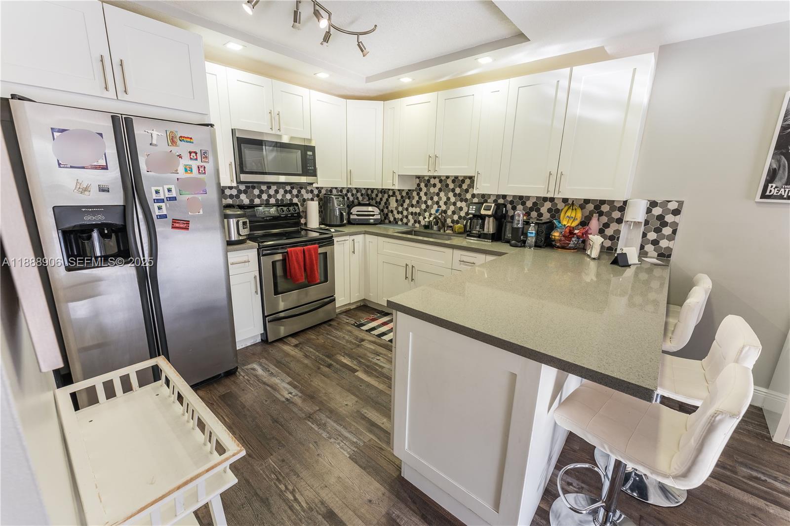 8810 Southwest 132nd Place, Unit 404DN Miami, FL 33186 - Photo 7 of 20 a kitchen with stainless steel appliances granite countertop a refrigerator a stove and white cabinets with wooden floor