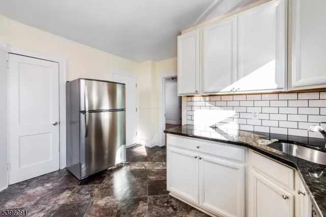 a kitchen with granite countertop a refrigerator and a sink