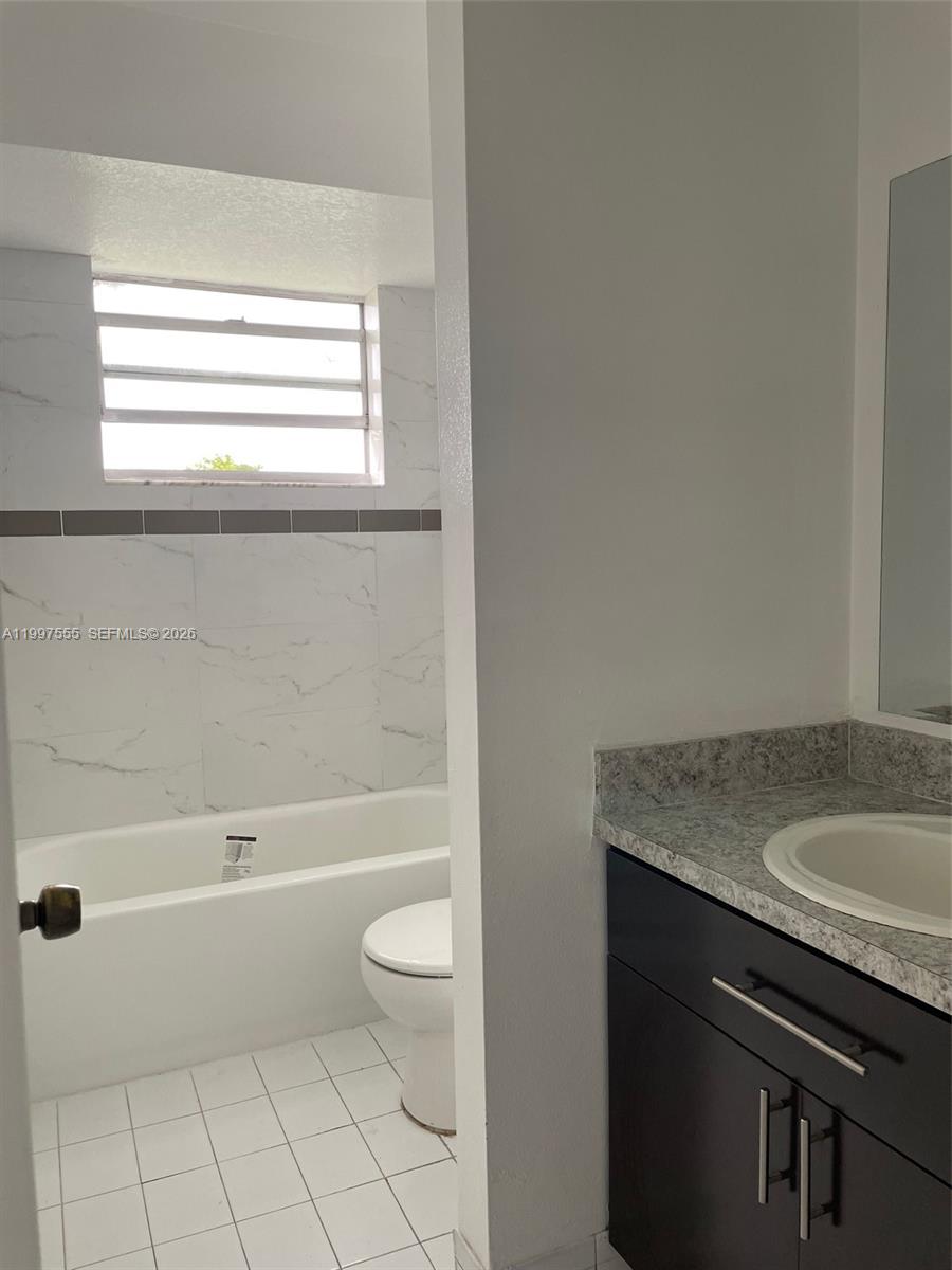 9771 Southwest 211 Street Cutler Bay, FL 33189 - Photo 17 of 19 a bathroom with a granite countertop sink a toilet and bathtub