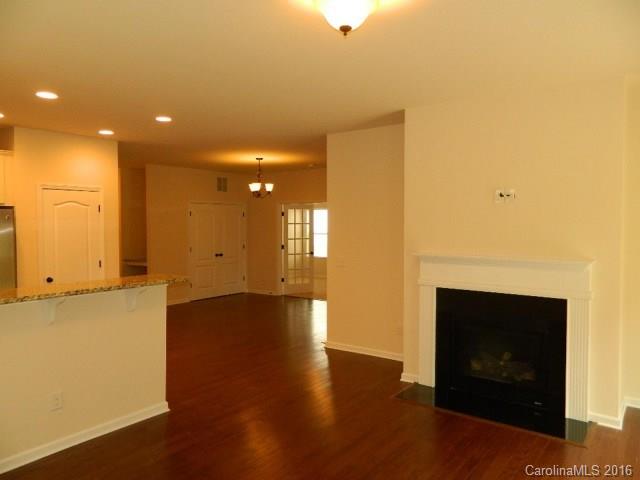 1532 Spring Blossom Trail, Unit SITE 41 Fort Mill, SC 29708 - Photo 9 of 20 a view of an empty room with wooden floor and a kitchen