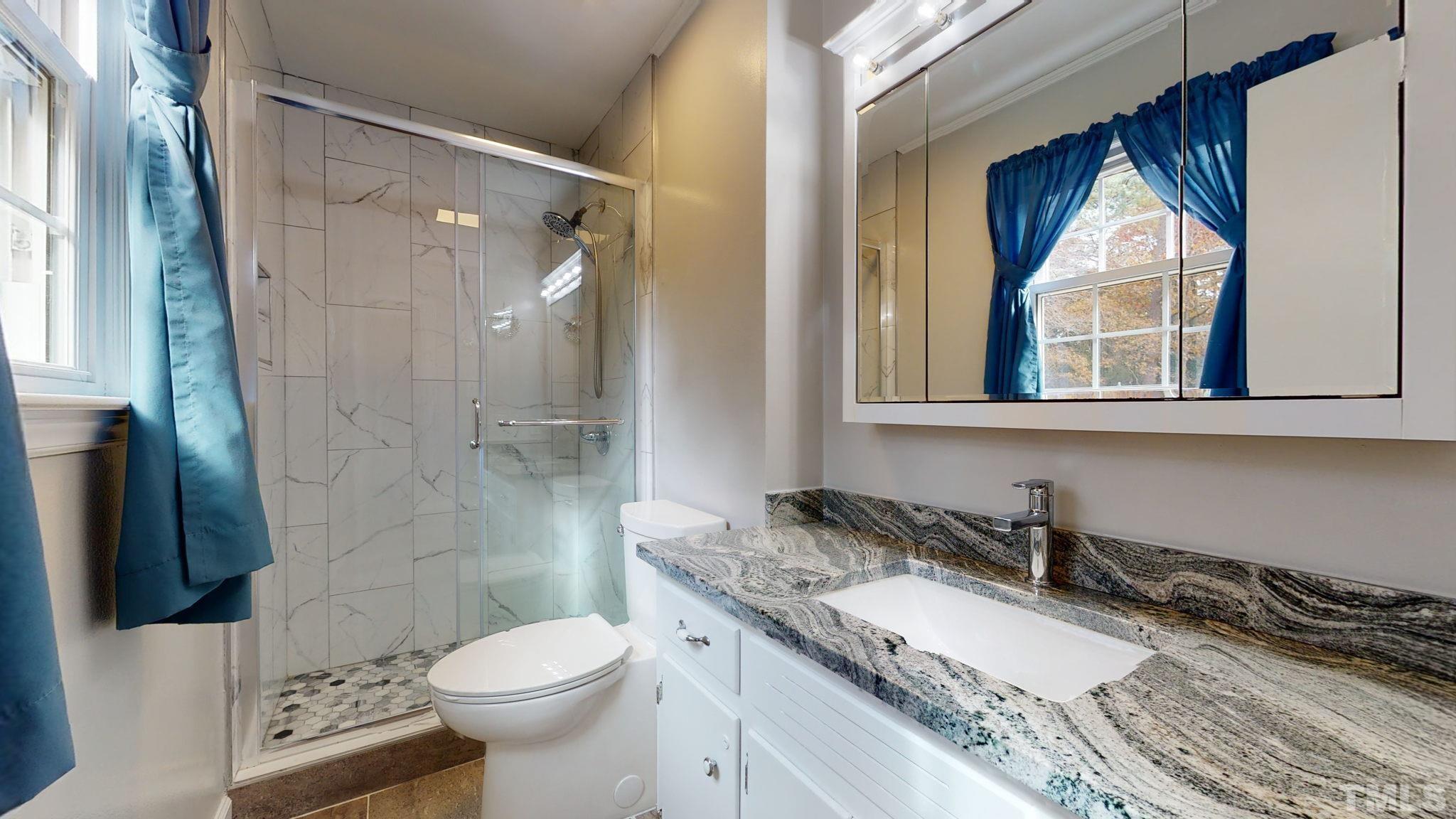7701 Leesville Road Raleigh, NC 27613 - Photo 27 of 33 a bathroom with a granite countertop toilet sink and shower
