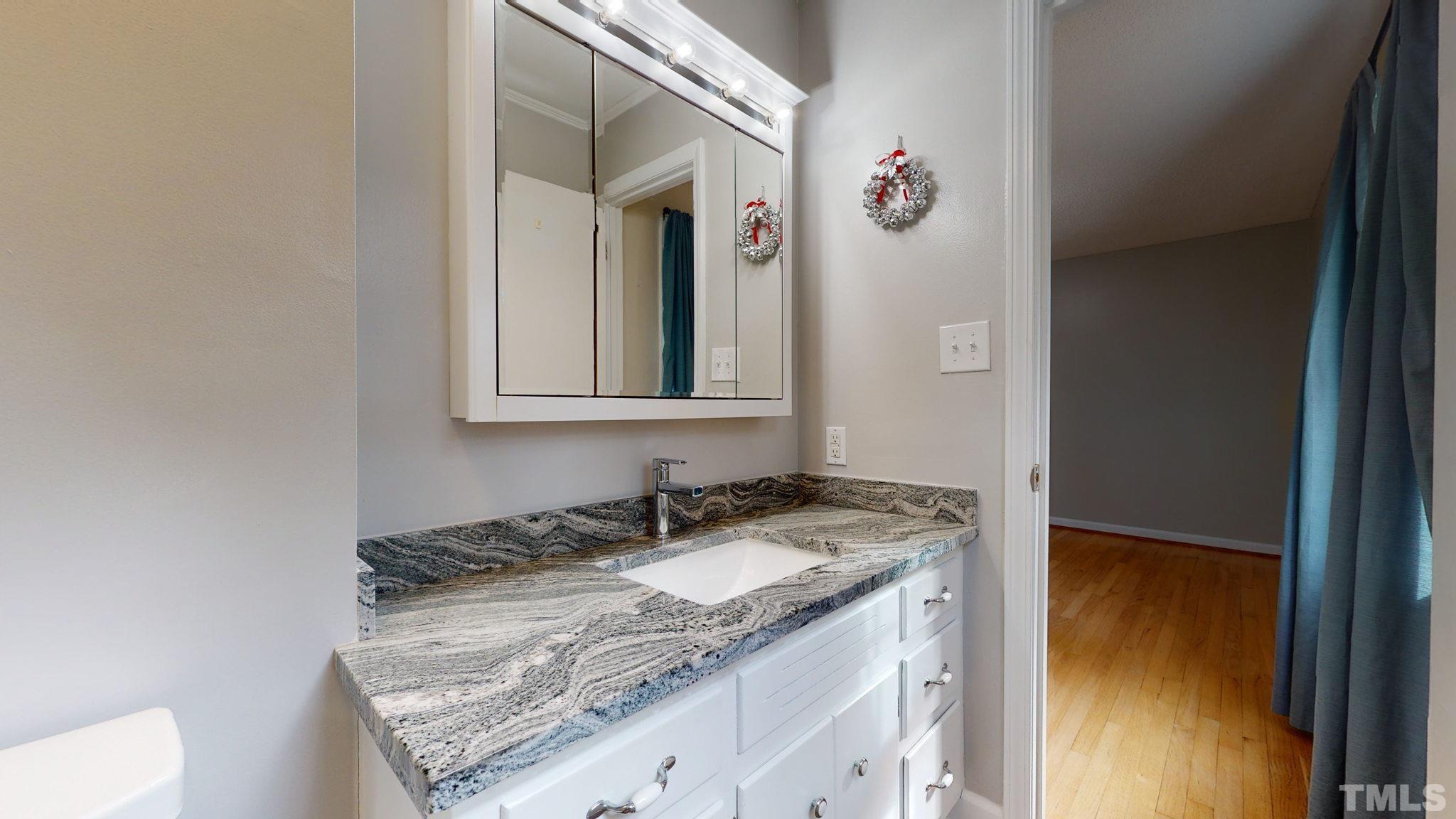 7701 Leesville Road Raleigh, NC 27613 - Photo 28 of 33 a bathroom with a granite countertop sink and a mirror