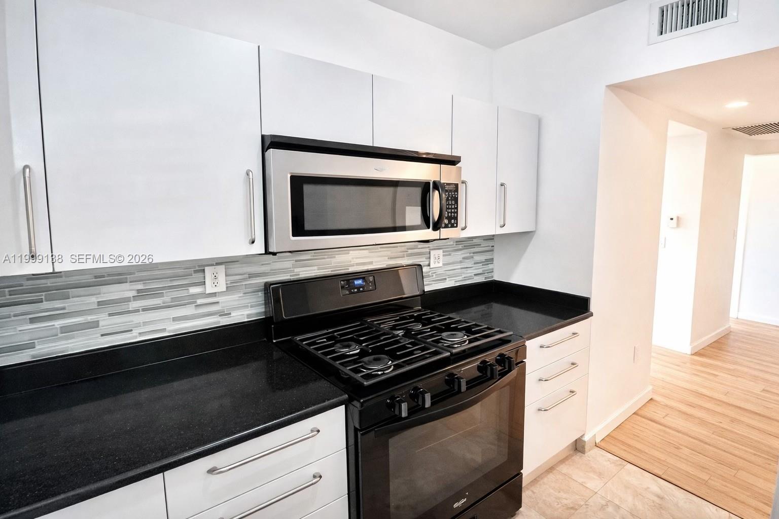 3915 Meridian Avenue, Unit 101 Miami Beach, FL 33140 - Photo 5 of 19 a kitchen with granite countertop cabinets and steel appliances
