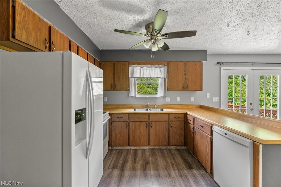 1827 Barth Road Belpre, OH 45714 - Photo 17 of 31 Kitchen featuring a textured ceiling, a wealth of natural light, brown cabinets, wood-type flooring, light countertops, white appliances, and ceiling fan