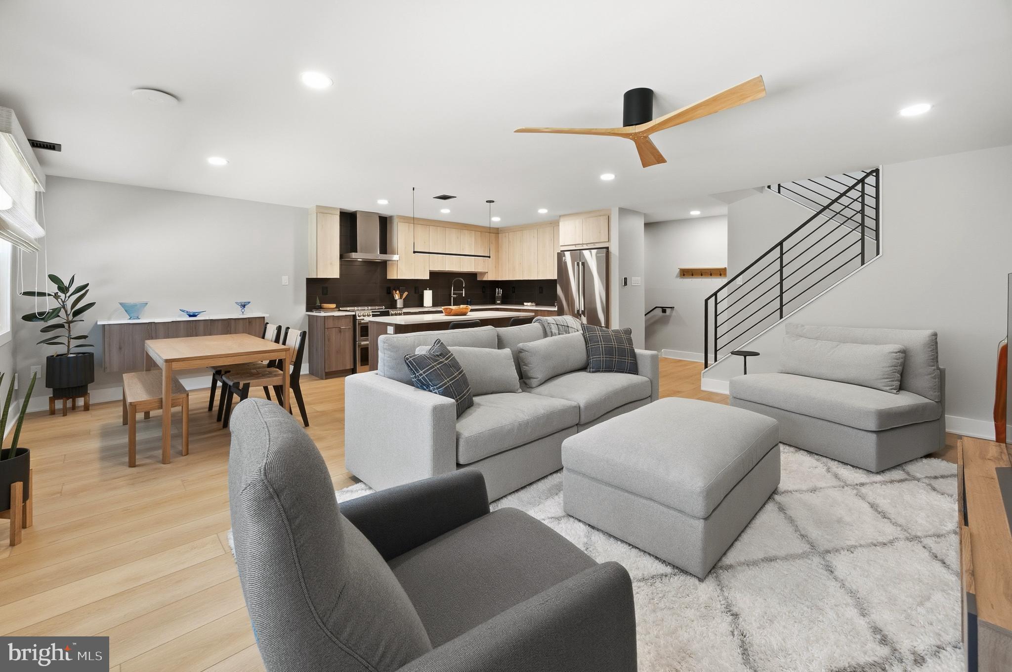 a living room with furniture kitchen view and a wooden floor