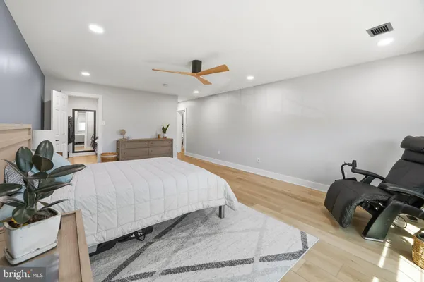 a spacious bedroom with a bed a couch and a potted plant on table