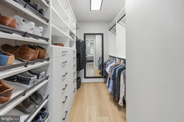 a view of walk in closet with clothes and shoes