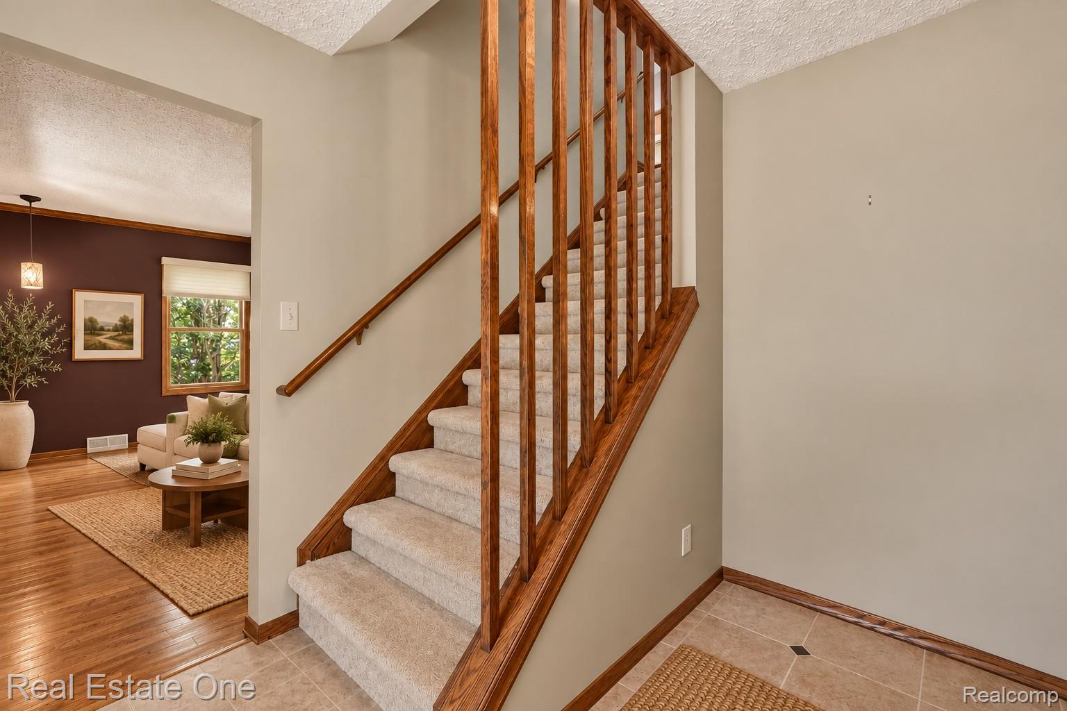 6039 Fish Lake Road Holly, MI 48442 - Photo 16 of 64 Virtually staged using AI-generated furnishings and décor. Welcoming entry showcasing the home's staircase, hardwood details, and connection to the adjoining living spaces.