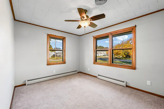 an empty room with ceiling fan and windows