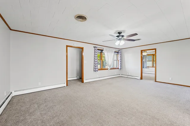 an empty room with ceiling fan and windows
