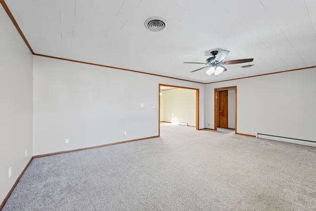 an empty room with chandelier fan and windows
