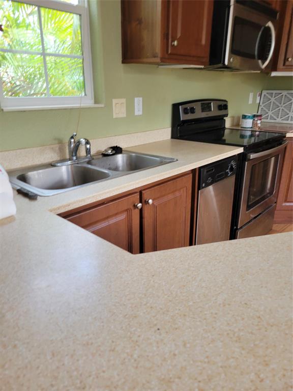 3759 Southwest 6th Avenue Okeechobee, FL 34974 - Photo 12 of 27 a kitchen with stainless steel appliances a sink a stove a microwave a sink and wooden cabinets