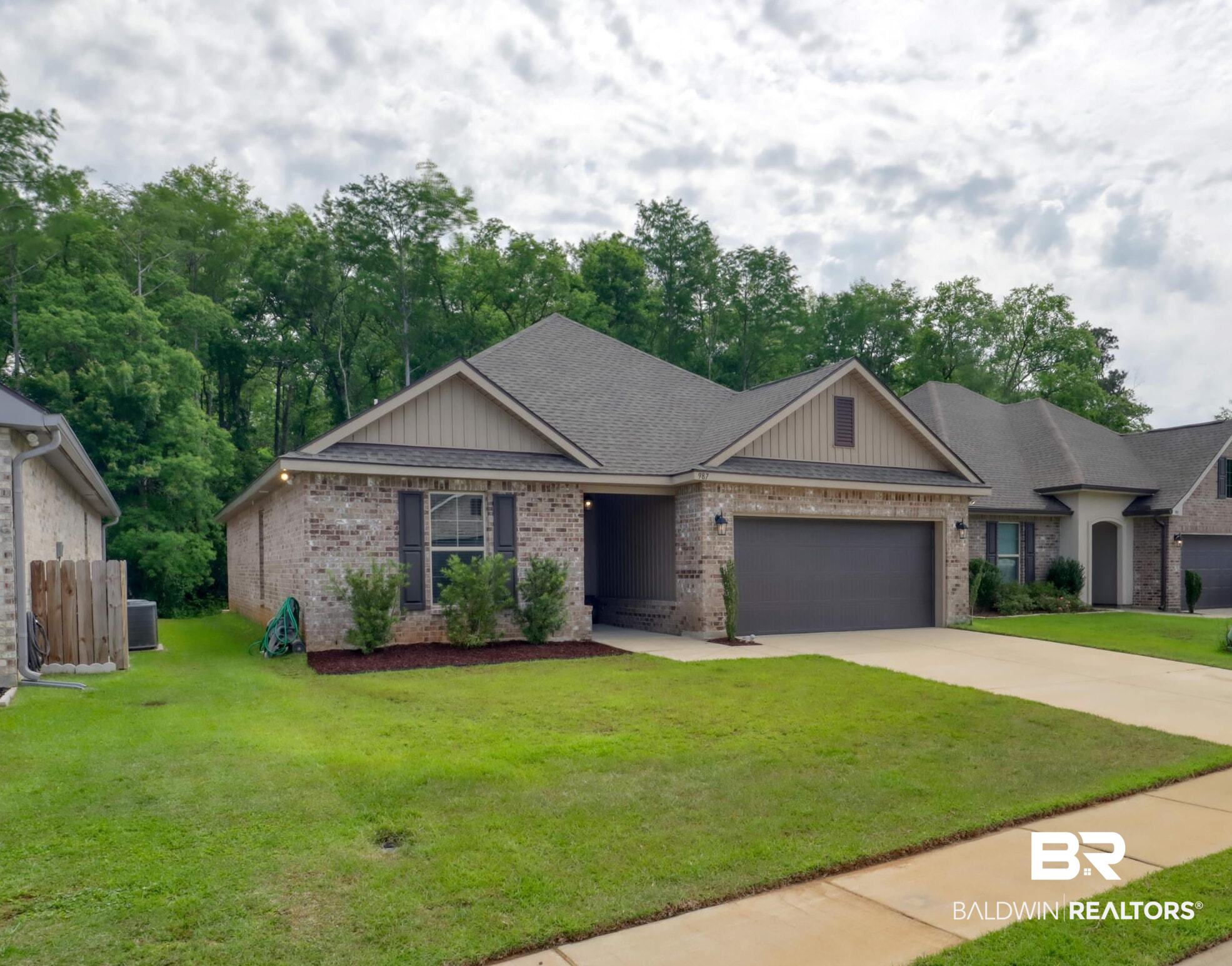 987 Gibson Court Foley, AL 36535 - Photo 1 of 34 View of front of home featuring driveway, a front yard, brick siding, fence, and an attached garage