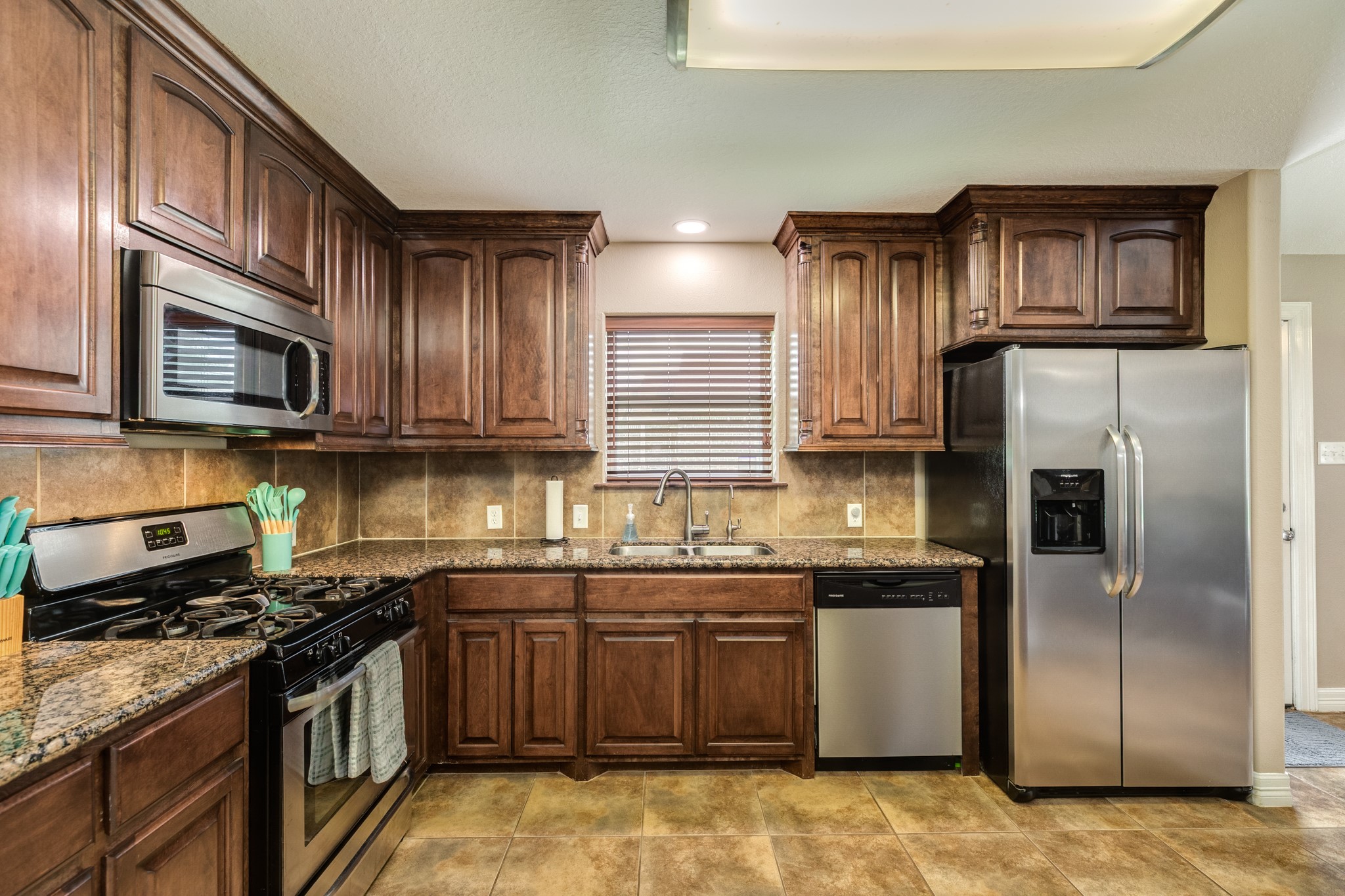 6108 Fox Ridge Drive Angleton, TX 77515 - Photo 12 of 26 a kitchen with stainless steel appliances granite countertop a stove top oven a sink dishwasher a refrigerator and cabinets with wooden floor