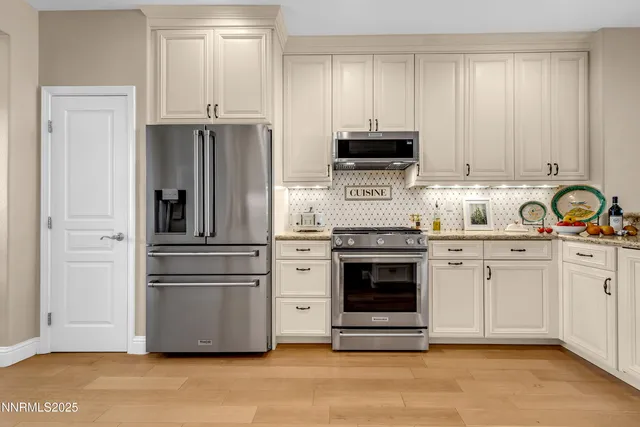 a kitchen with refrigerator a stove a sink and white cabinets