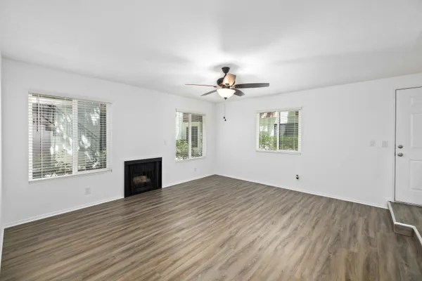 a view of an empty room with a window and wooden floor