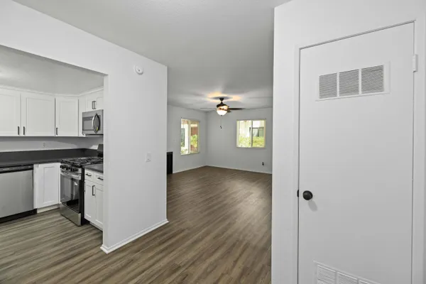 a view of a kitchen from the hallway with a window and wooden floor