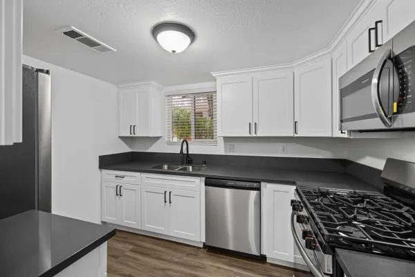 a kitchen with granite countertop a sink a stove and cabinets