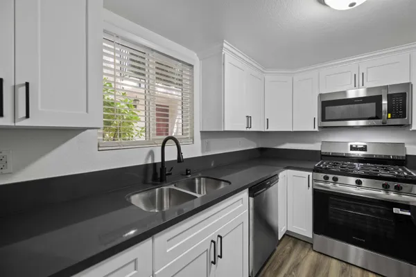 a kitchen with stainless steel appliances granite countertop a sink a stove a microwave and wooden cabinets