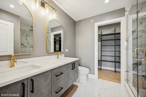 a bathroom with a granite countertop sink a toilet a mirror and shower